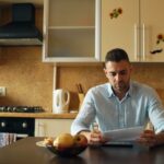 Man reading document at kitchen table with coffee