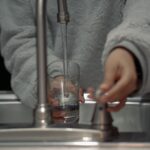 person holding clear glass container